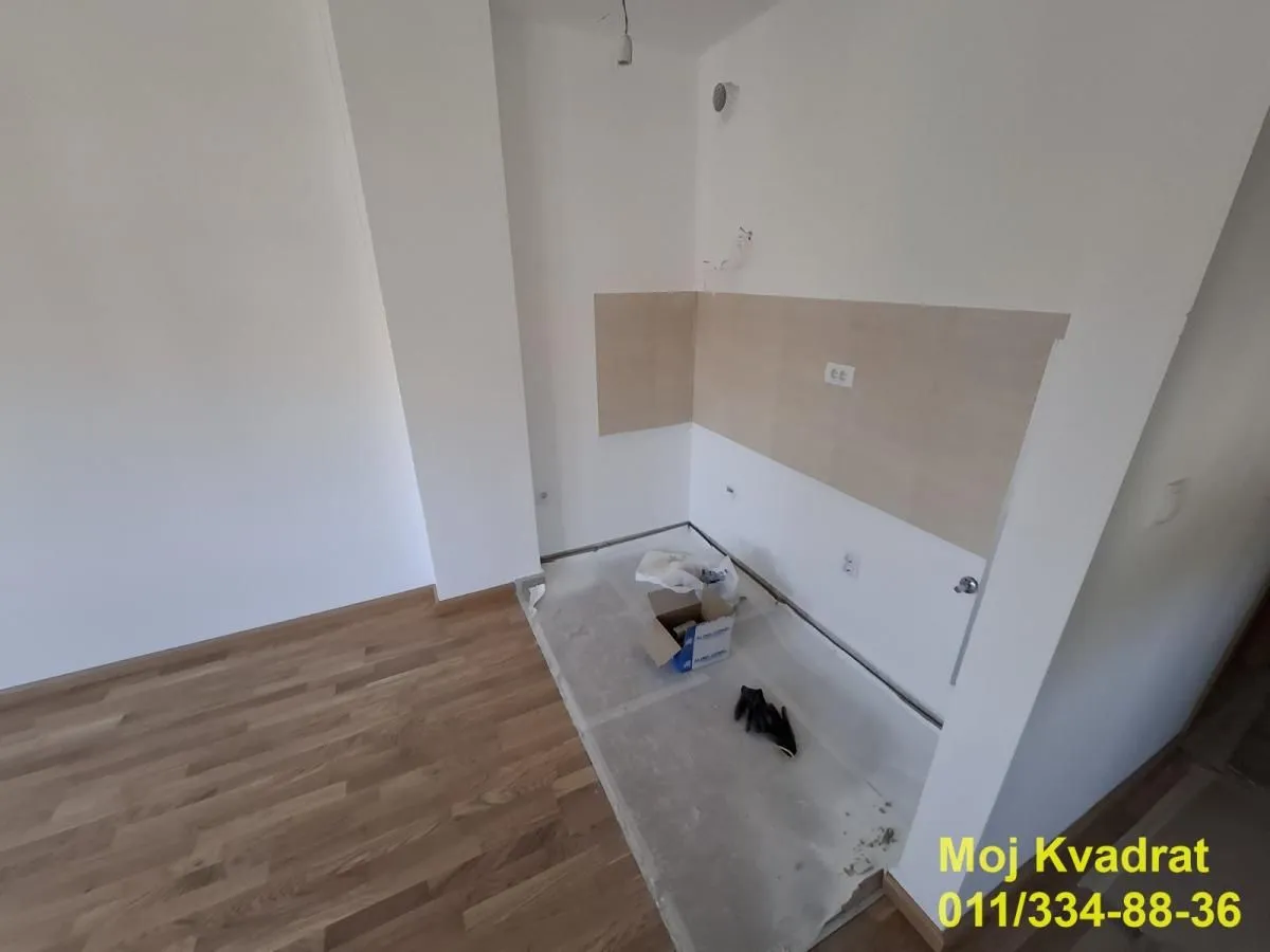 Prazan prostor predviđen za kuhinju sa postavljenim keramičkim pločicama i drvenim podom.