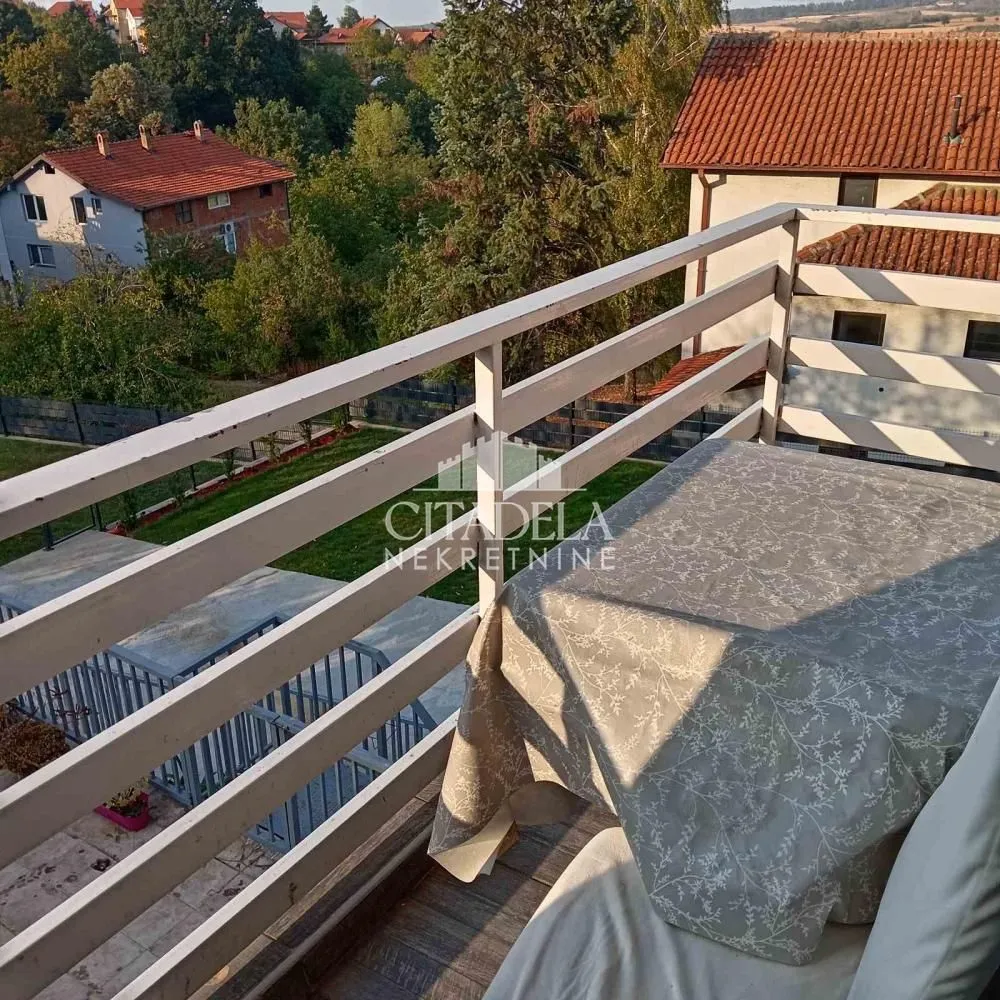 Balkon sa ogradom i pogledom na okolno zelenilo i objekte.