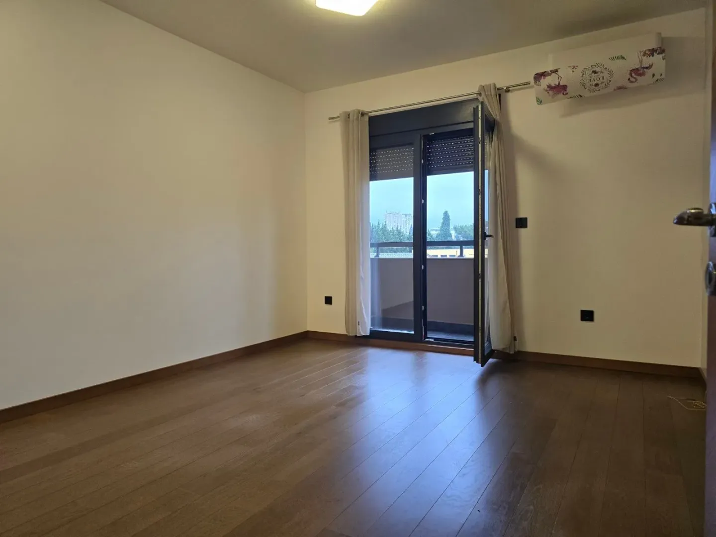 Empty room with wooden flooring and access to a terrace.