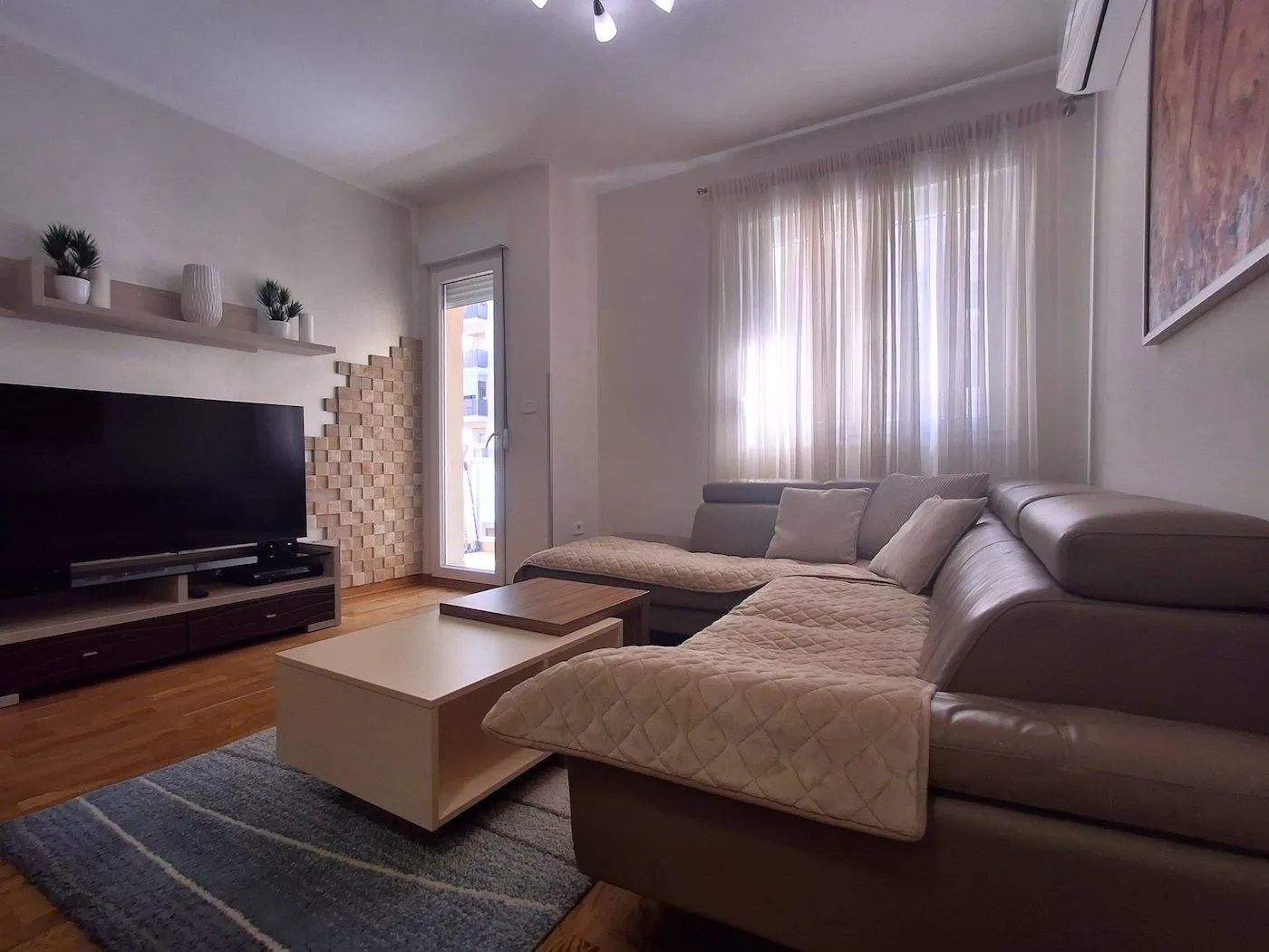 Modern and bright living room with a sectional sofa, TV, and access to the terrace.
