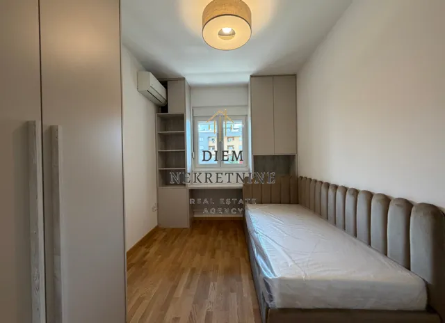 Small bedroom with a bed, built-in wardrobes, and a desk by the window.