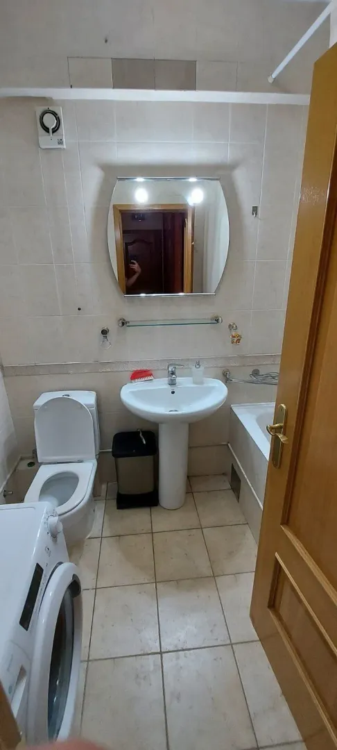 Kupatilo sa lavaboom, ogledalom i veš mašinom.