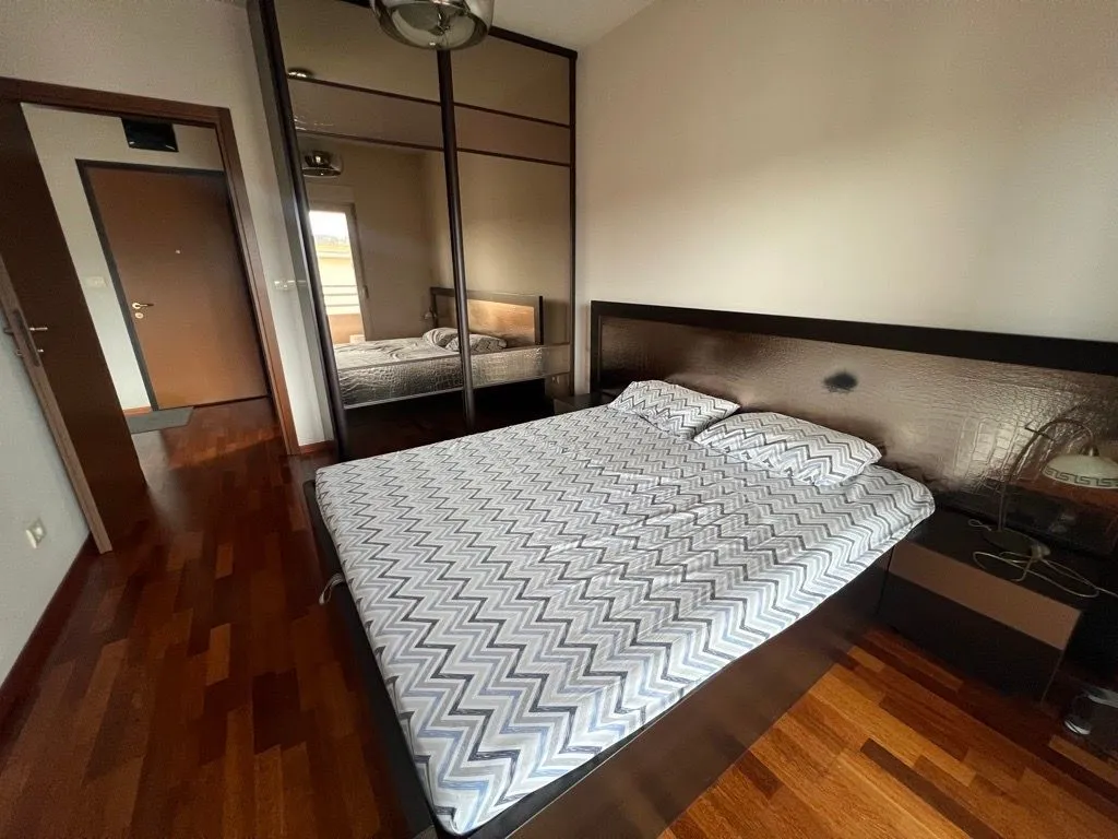 Furnished bedroom with a double bed and a large mirrored wardrobe.