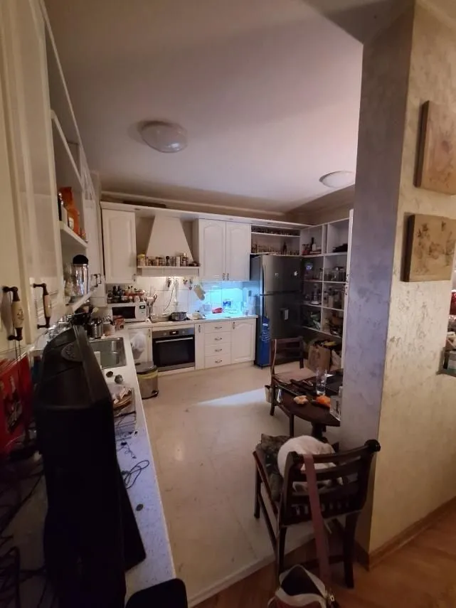 A spacious kitchen with white cabinets and a dining table.