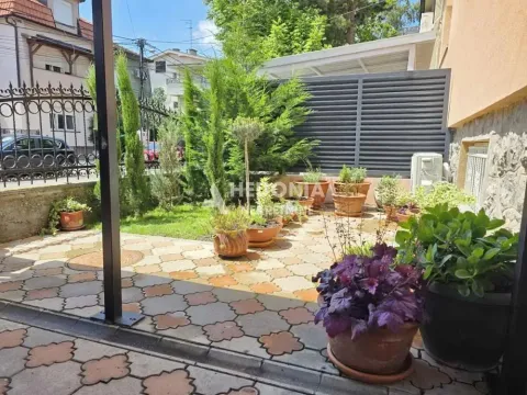 Uređeno dvorište sa popločanim delom, travnjakom i saksijama sa biljkama. - image 16