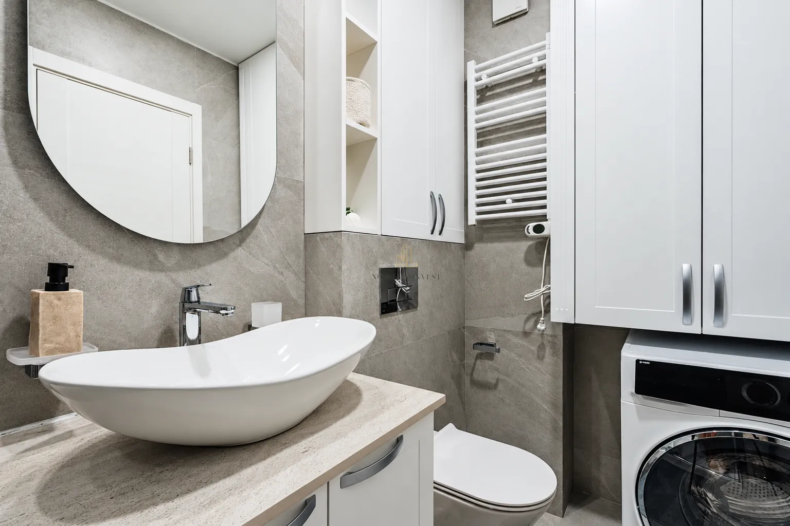 Modern equipped bathroom with a washbasin, toilet, built-in cabinets and a washing machine.