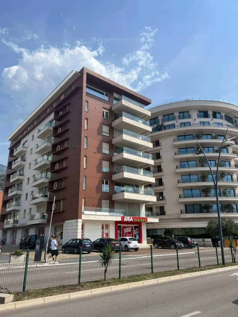 Spoljašnji izgled moderne višestambene zgrade sa marketom u prizemlju.