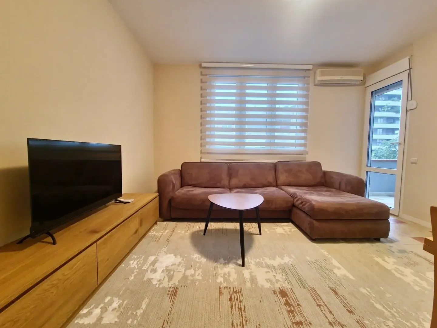 Living room with a sectional sofa, TV, and access to the terrace.