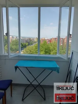 Zastakljeni balkon sa stalkom za sušenje veša i pogledom na grad. - image 8