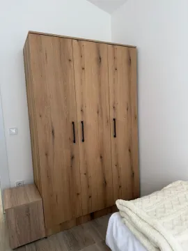 Spavaća soba sa velikim drvenim ormarom i krevetom. - image 5