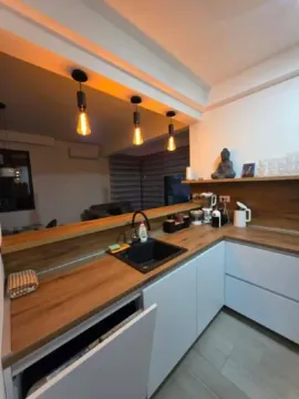 Modern kitchen with white cabinets, wooden countertop and a breakfast bar. - image 4