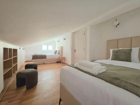 Prostrana potkrovna spavaća soba sa dva kreveta i drvenim podom. - image 10
