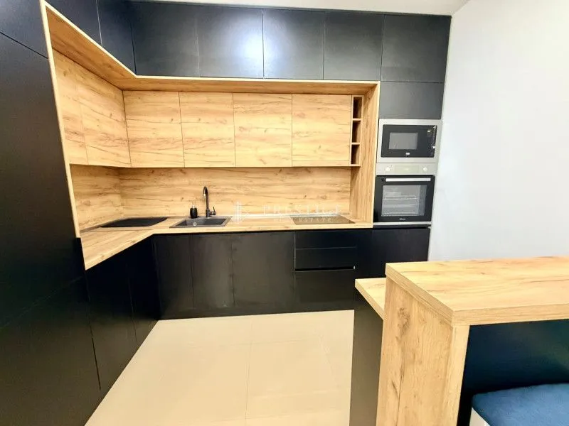 Moderna kuhinja sa crnim elementima i drvenim detaljima.