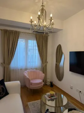 Dnevna soba sa udobnom foteljom, kaučem, televizorom i ukrasnim lusterom. - image 6