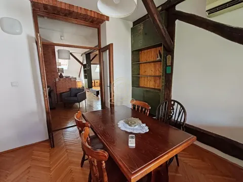 Dining area with a wooden table and chairs in an attic with wooden beams. - image 14