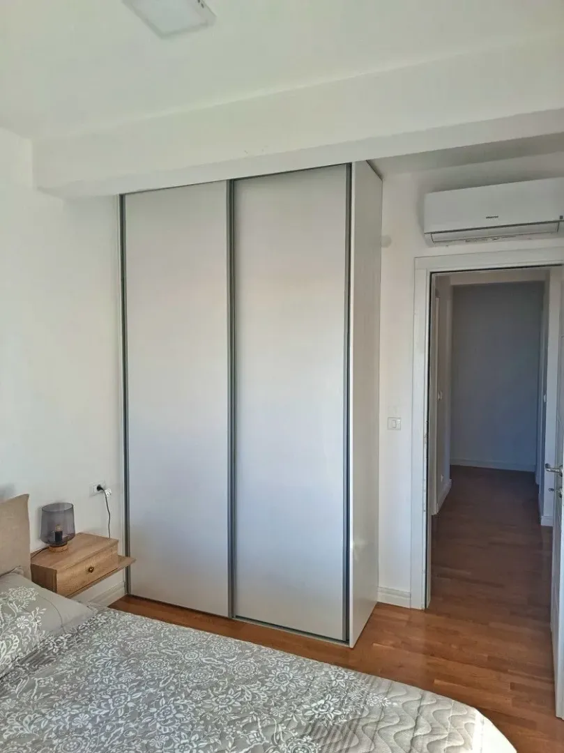 Spavaća soba sa velikim ugradnim garderoberom, krevetom i klima uređajem.