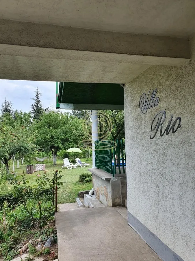 Pogled sa ulaza na dvorište i zelenu površinu sa drvećem.