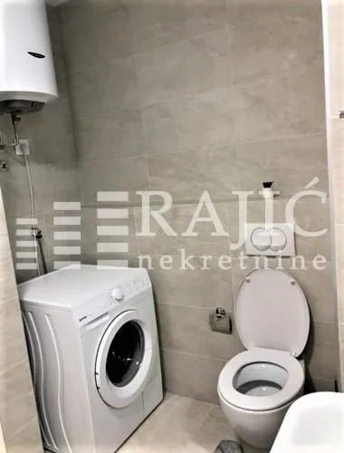 View of the bathroom with a washing machine and toilet.