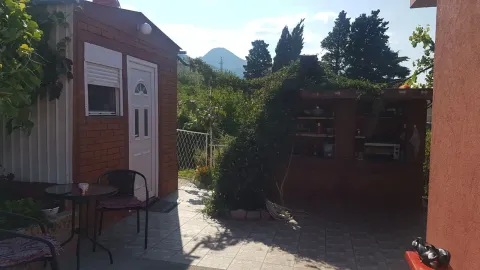 Dvorište kuće sa popločanom terasom, stolom i pogledom na okolno zelenilo. - image 4