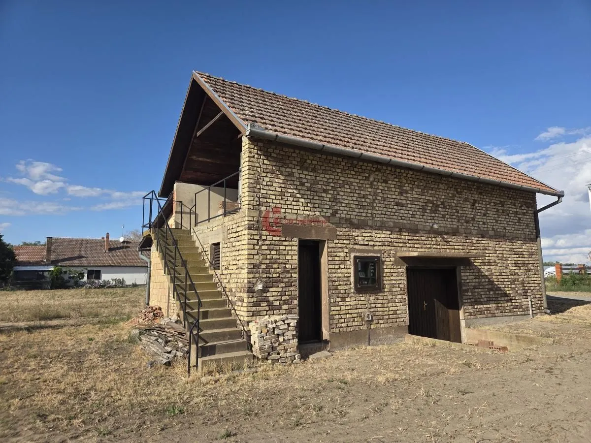 Pogled na spoljašnjost kuće od cigle sa spoljnim stepenicama i dvorištem.