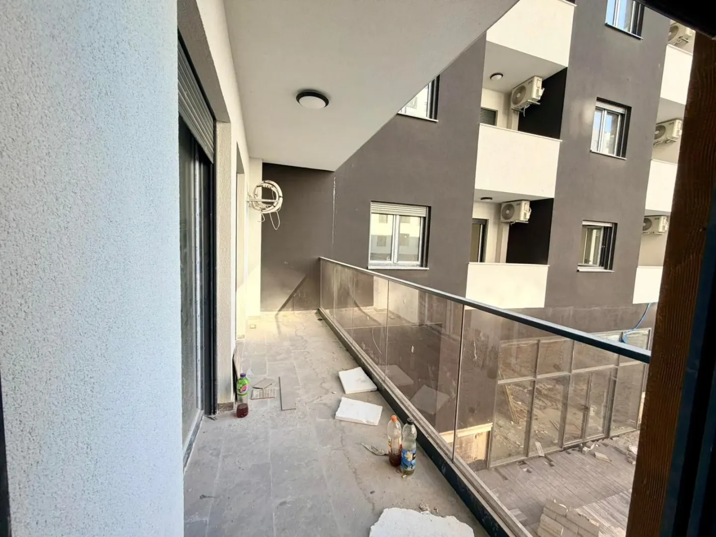 Nezavršeni balkon sa staklenom ogradom i građevinskim otpadom.