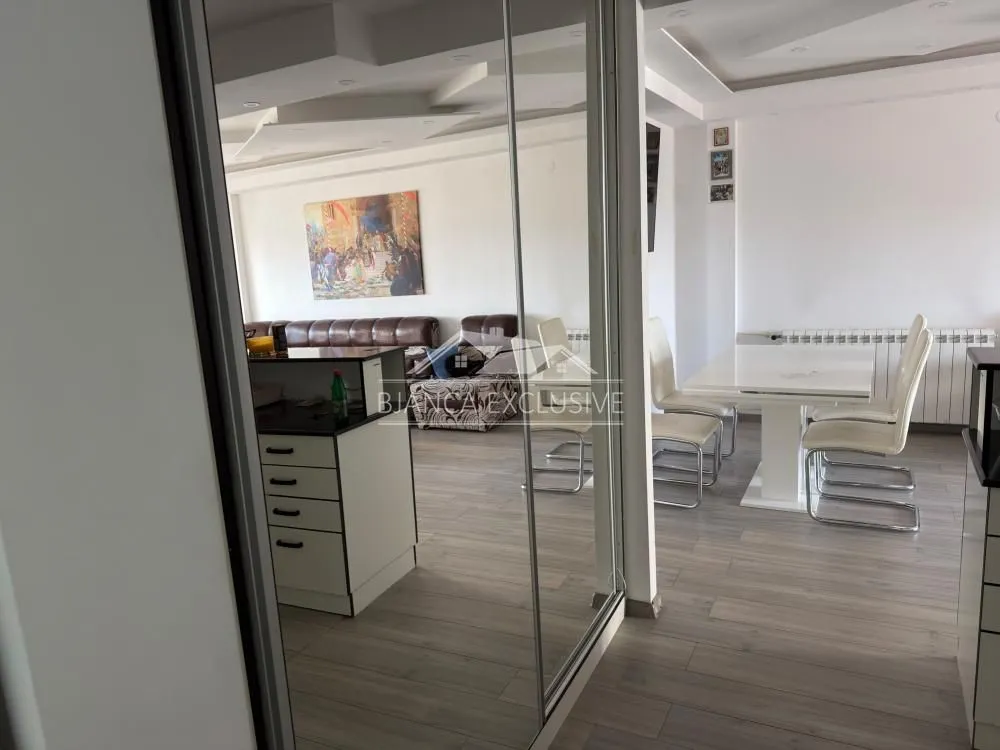 Pogled iz hodnika na dnevni boravak i trpezariju sa nameštajem.