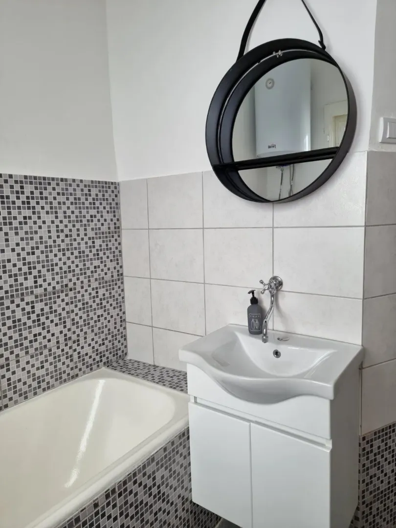 Bathroom with a vanity, cabinet, mirror, and bathtub.