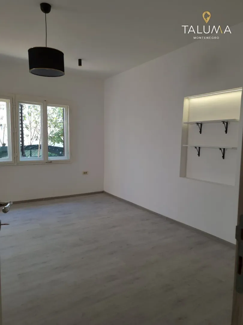 Empty room with light walls, laminate flooring, and built-in shelving.