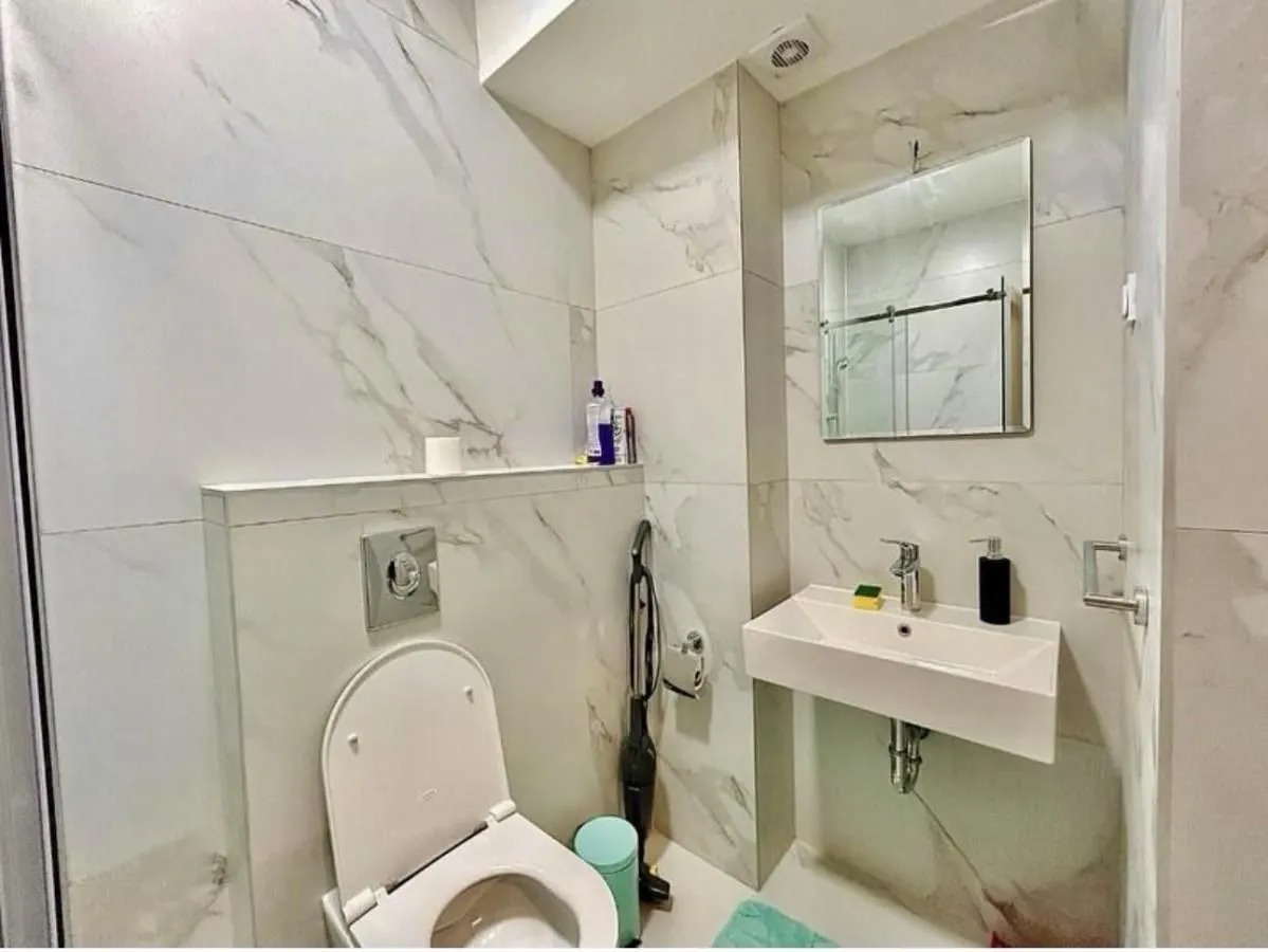 Savremeno opremljeno kupatilo sa mermernim pločicama, umivaonikom i WC šoljom.