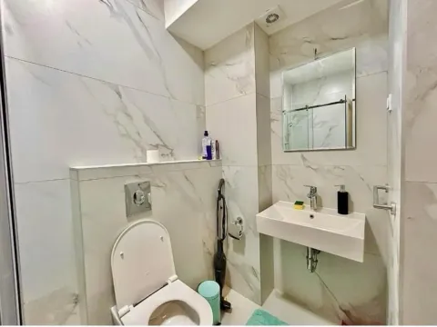 Savremeno opremljeno kupatilo sa mermernim pločicama, umivaonikom i WC šoljom. - image 6