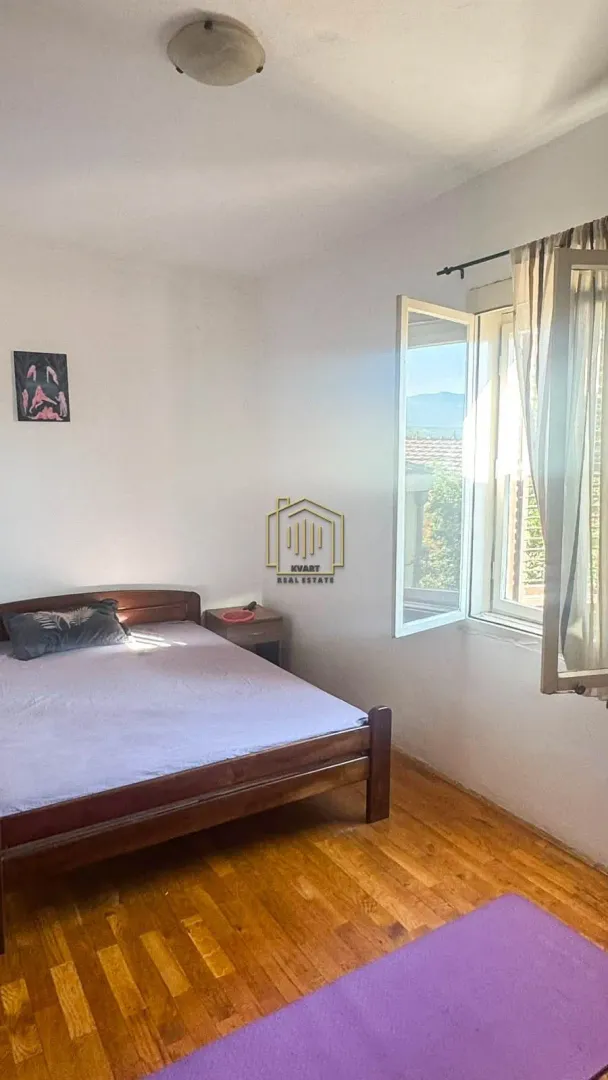 Spavaća soba sa bračnim krevetom i prozorom koji gleda spolja.