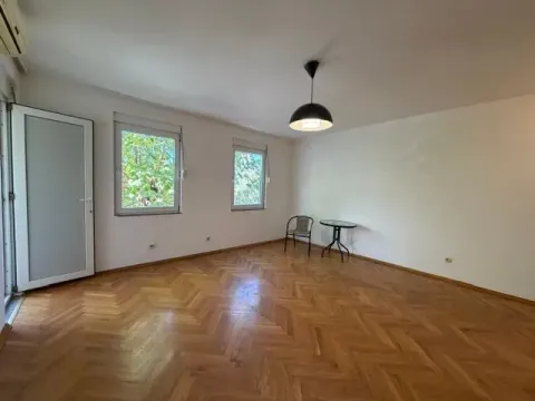 Prazna prostorija sa parketom, bijelim zidovima i izlazom na terasu. - image 2