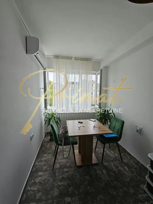 Small dining area with a table and green chairs in front of the window.