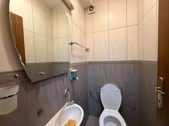 Manje kupatilo sa WC šoljom, umivaonikom i ogledalom.