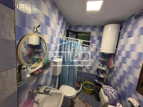 Manje kupatilo obloženo plavim pločicama sa umivaonikom, wc šoljom i tuš kabinom. - image 11