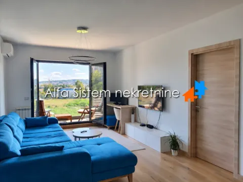 Dnevna soba sa plavom ugaonom garniturom, TV-om i izlazom na terasu. - image 9