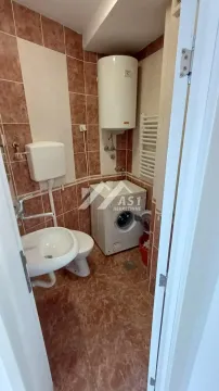 Smaller bathroom with a sink, toilet, water heater, and washing machine. - image 3