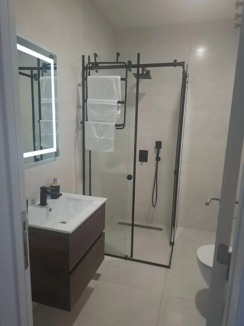 Modern bathroom with a vanity, walk-in shower, and illuminated mirror.