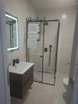 Modern bathroom with a vanity, walk-in shower, and illuminated mirror. - image 4