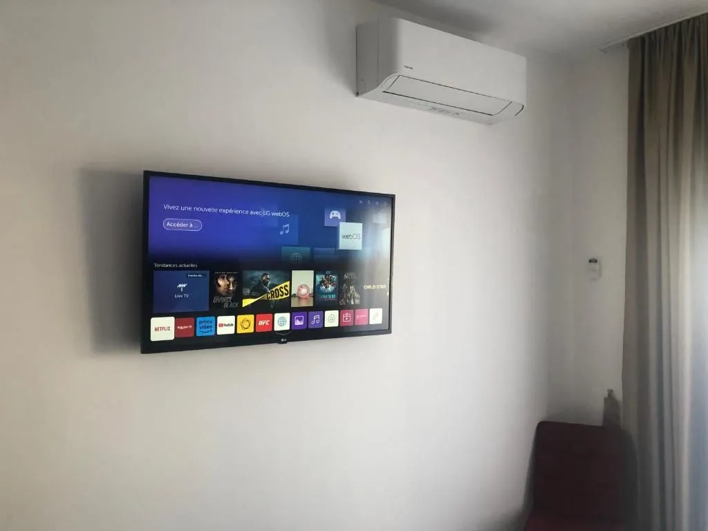 Televizor postavljen na zid u sobi sa klima-uređajem.