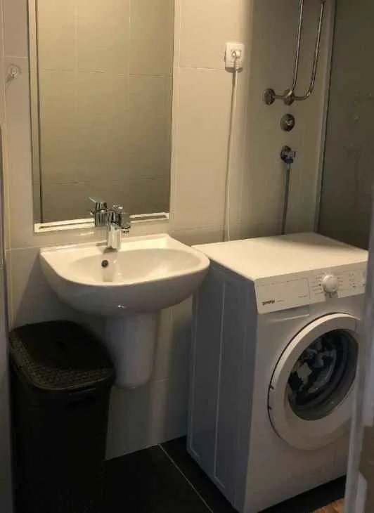 Kupatilo sa umivaonikom, ogledalom i veš mašinom.
