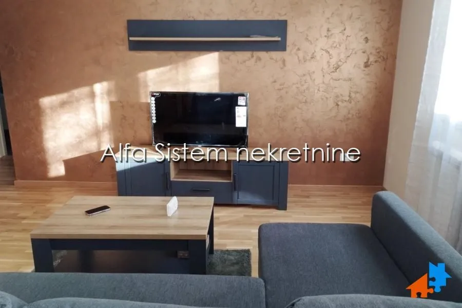 Living room with a sofa, coffee table, and a wall-mounted TV.