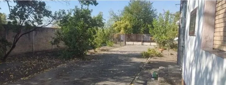 Dvorište kuće sa zelenilom i ogradom.