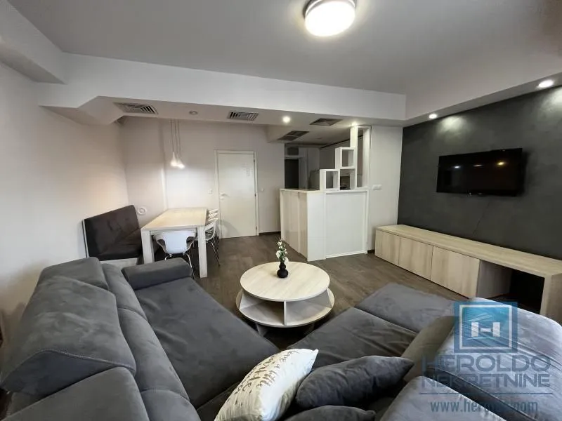 Living room with a sofa, dining area, and wall-mounted TV.