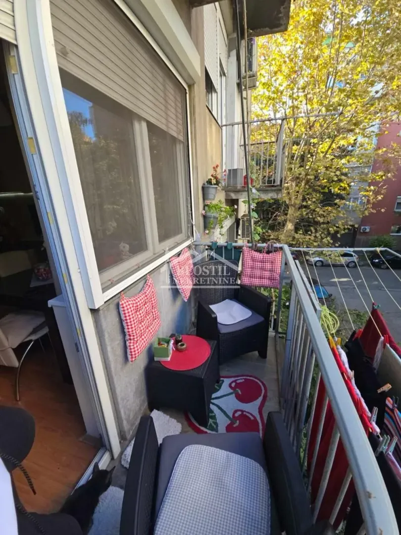 Manji namešten balkon sa garniturom za sedenje i pogledom na ulicu.