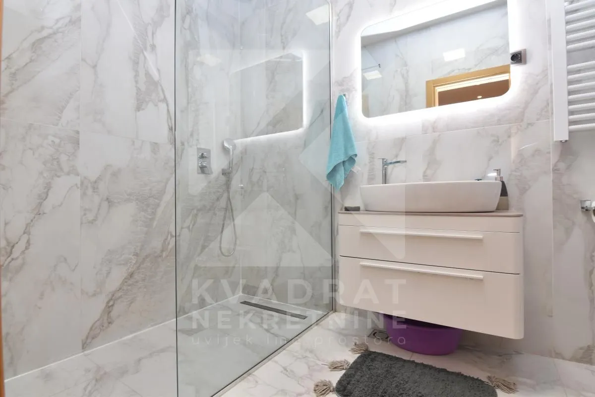 Modernly equipped bathroom with a walk-in shower and washbasin.