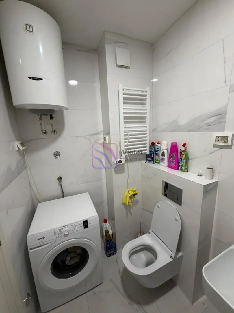 Manje kupatilo sa WC šoljom, veš mašinom i bojlerom.