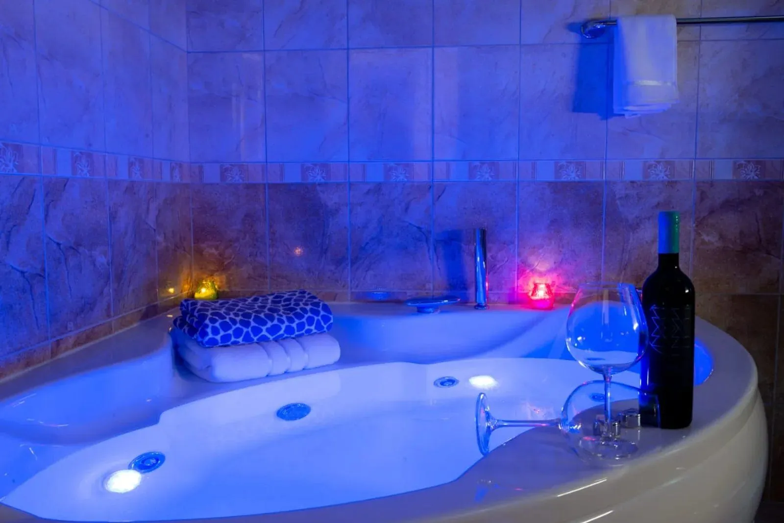 Kutni hidromasažni jacuzzi u moderno uređenom kupatilu sa ambijentalnim osvjetljenjem.