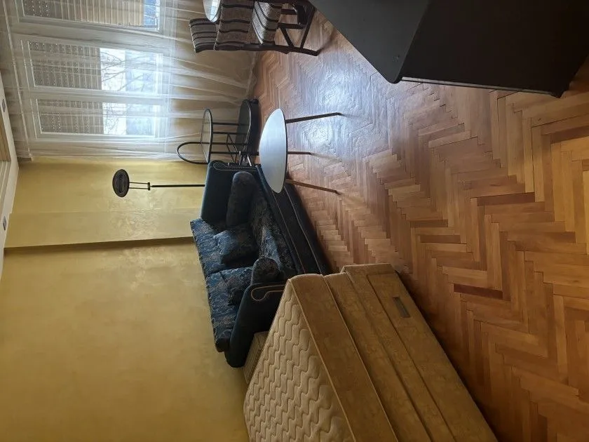Dnevna soba sa garniturom, parketom i prozorom.
