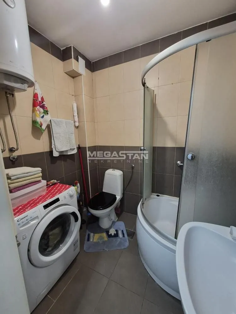 Kupatilo opremljeno tuš kabinom, WC šoljom, umivaonikom i veš mašinom.